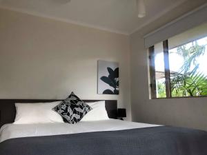 a bed with a black and white pillow in a bedroom at Reef Terraces on St Crispins - Villa 2 in Port Douglas