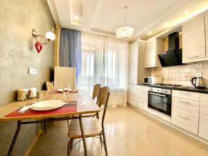a kitchen with a table and chairs in a room at ApartPoltava Світлі та просторі двокімнатні апартаменти в новобудові, закритий паркінг , ЦЕНТР МІСТА, банківський ЧЕК in Poltava +19 photos