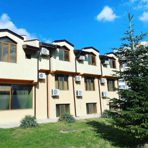 ein Apartmenthaus mit einem Baum davor in der Unterkunft Interrum Hotel in Razgrad