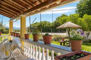 a porch with potted plants and an umbrella at Teta's Holiday Home in Melíkia