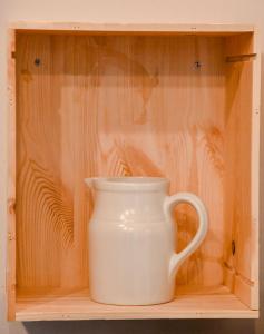 a white cup sitting on a wooden shelf at La Chaumière, centre historique, fibre, ESS, rez-de-chaussée, BedinShop in Romans-sur-Isère