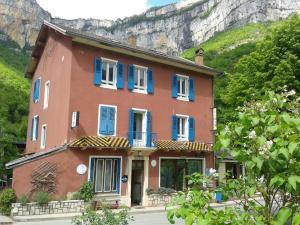 czerwony dom z niebieskimi okiennicami na górze w obiekcie Le Jorjane w mieście Choranche