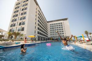 two people playing in the swimming pool at a hotel at Rove La Mer Beach in Dubai