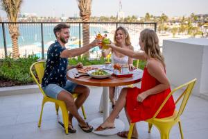 a group of people sitting around a table with drinks at Rove La Mer Beach, Jumeirah in Dubai
