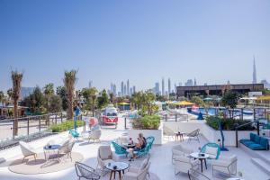 a group of people sitting on a roof with chairs and tables at Rove La Mer Beach, Jumeirah in Dubai