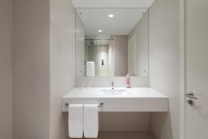 a white bathroom with a sink and a mirror at Rove La Mer Beach, Jumeirah in Dubai
