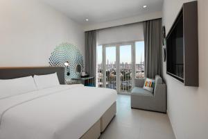 a bedroom with a large bed and a large window at Rove La Mer Beach, Jumeirah in Dubai