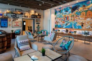 a restaurant with chairs and tables and a large mural at Rove La Mer Beach, Jumeirah in Dubai