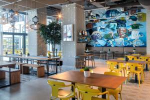 a restaurant with wooden tables and yellow chairs at Rove La Mer Beach, Jumeirah in Dubai