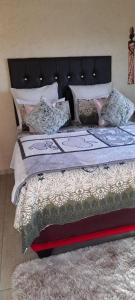 a bed with a black headboard and pillows on it at Lapa la Bakgatlha in Soweto