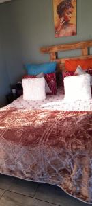 a bed with a comforter and pillows on it at Lapa la Bakgatlha in Soweto