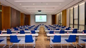 a conference room with tables and chairs and a screen at Holiday Inn Express Luanchuan by IHG in Luanchuan