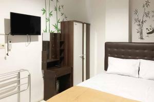 a bedroom with a bed and a flat screen tv at SAS Guest House Mitra RedDoorz At Darmo Park 2 Surabaya in Surabaya +12 photos