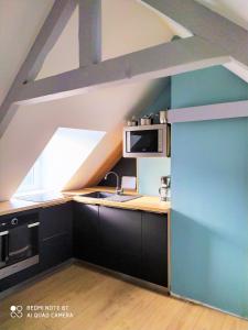 a kitchen with black cabinets and a blue wall at La Nacelle, classée 3 étoiles, vue dégagée port et mer in Le Tréport