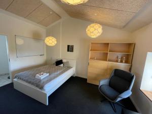 een slaapkamer met een bed en een stoel erin bij Essenbaekgaard B&B in Assentoft