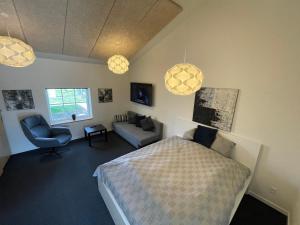 una camera con letto, divano e luci a ciondolo di Essenbaekgaard B&B a Assentoft