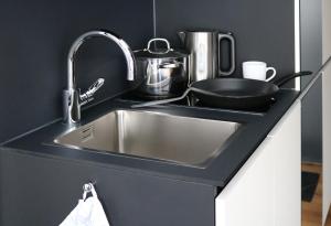 a kitchen counter with a stainless steel sink at KUF Hotel by WMM Hotels in Kufstein