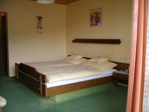 1 dormitorio con 1 cama grande con sábanas y almohadas blancas en Pension Williams, en Seebach