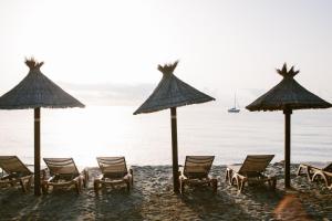 - un groupe de chaises longues et de parasols sur une plage dans l'établissement Domaine Naturiste de Riva Bella, à Linguizzetta