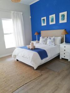 um quarto com uma cama grande e uma parede azul em Akwa em Hermanus