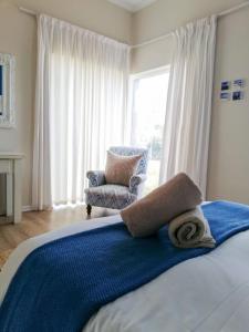 a bedroom with a bed and a chair and a window at Akwa in Hermanus