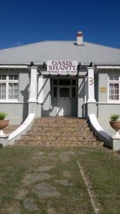 un edificio blanco con un cartel en la parte delantera en Oasis Shanti Backpackers en Oudtshoorn