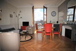 ein Wohnzimmer mit einem Tisch, Stühlen und einer Uhr in der Unterkunft L'Anvers vue port de plaisance 2 à 3 pers in Dieppe