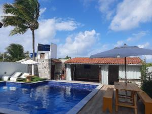 uma piscina com um guarda-sol ao lado de uma casa em Casa em Jacumã com piscina e vista MAR em Conde