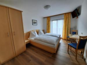 una camera da letto con un letto, un tavolo e una finestra di Pension Aberger a Saalbach Hinterglemm
