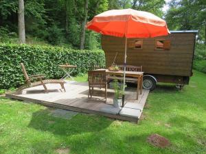 una terraza de madera con mesa y sombrilla en Bienenwagen der Naturheilpraxis Melchger, en Wildberg