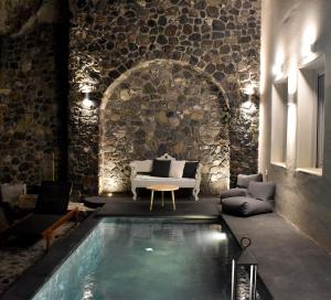a swimming pool in a room with a stone wall at Deep Earth Villas in Éxo Goniá