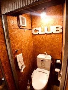 a bathroom with a toilet and a club sign on the wall at Guesthouse Yadocurly in Onomichi