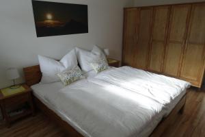 a bed with white sheets and pillows in a bedroom at Bungalow Baloo Ferienhaus in Sankt Johann in Tirol