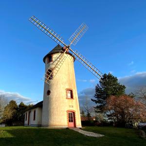 um moinho de vento em cima de um campo de relva em LE MOULIN DES GARDES em Saint-Georges-du-Puy-de-la-Garde