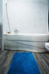 baño con bañera blanca y alfombra azul en The Pearl of Esztergom, en Esztergom