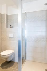 a bathroom with a toilet and a glass shower at Résidence Le Marly in Annemasse