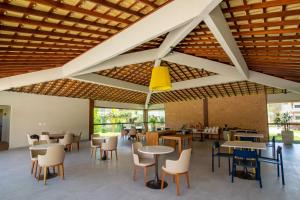 a restaurant with tables and chairs and a yellow light fixture at Areia Azul Aparts Brazil - Imbassai Ykutiba in Imbassai