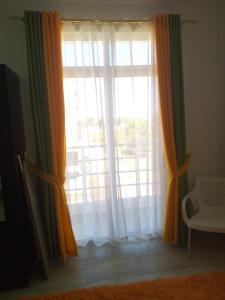 una ventana con cortinas de color naranja y verde en una habitación en Pride Studio Mtwapa en Mombasa
