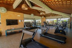 a gym with several cardio machines and a flat screen tv at Areia Azul Aparts Brazil - Imbassai Ykutiba in Imbassai
