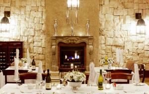 a dining room with a fireplace and tables with wine bottles at La Villa Vita in Nelspruit