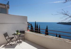 balcón con mesa, sillas y vistas al agua en Apartments Villa Ari, en Dubrovnik