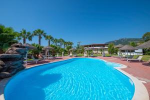 a swimming pool at a resort with palm trees at Hotel Rurale Orti di Nora & SPA in Santa Margherita di Pula