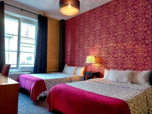 a hotel room with two beds and a red wall at Hotel Mondial in Tours