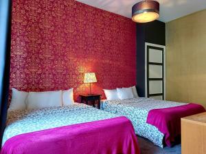 2 camas en una habitación con una pared roja en Hotel Mondial en Tours