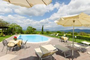 einen Pool mit Tischen, Stühlen und einem Sonnenschirm in der Unterkunft Agriturismo San Francesco in Cortona