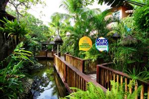 a wooden bridge over a pond in a garden at Beijamar Praia Hotel in Arraial d'Ajuda