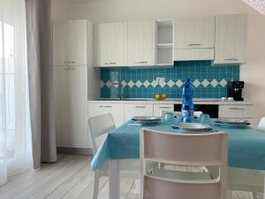 a kitchen with a blue table and white cabinets at Le ciliegie: appartamento moderno Isola Rossa in Isola Rossa +21 photos