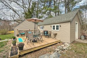 a deck with a table and chairs and an umbrella at Remodeled Farmhouse in Waterford Near 2 Beaches! in Waterford
