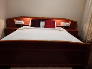 Una cama con dos almohadas rojas encima. en Sétány apartman, en Mórahalom