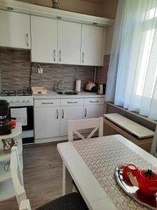una cocina con armarios blancos y una mesa con un tazón. en Sétány apartman en Mórahalom